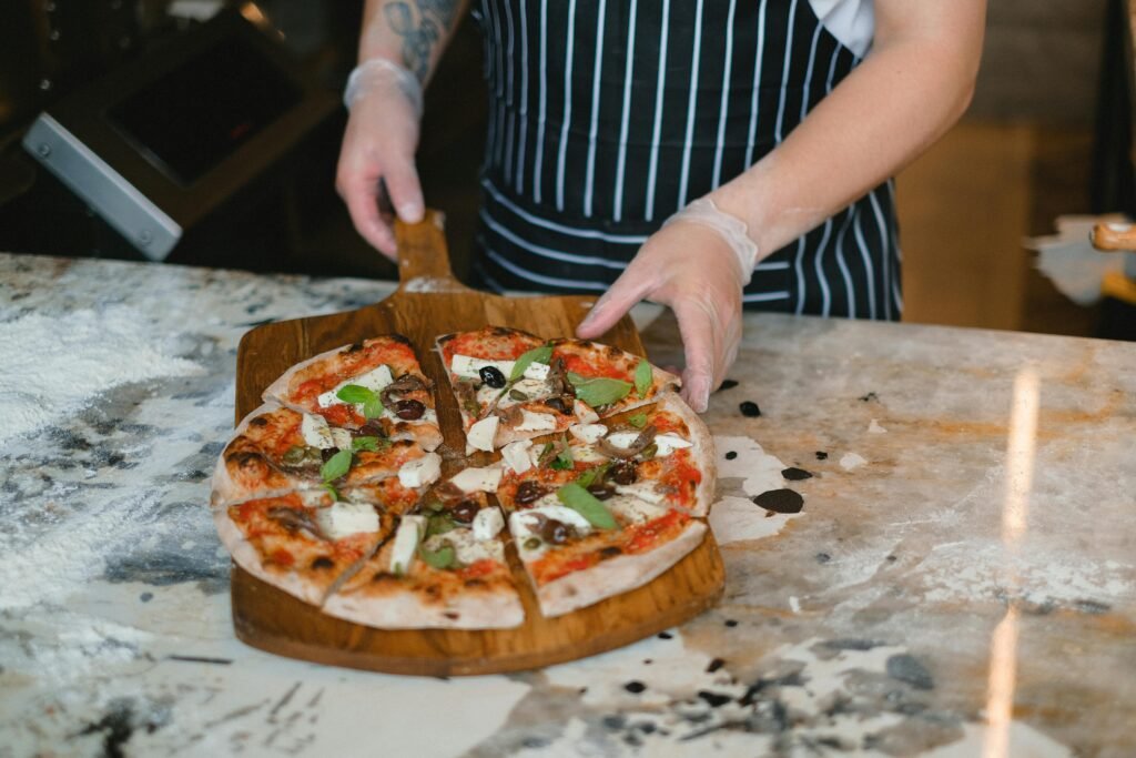 Person Holding a Pizza on a Serving Board